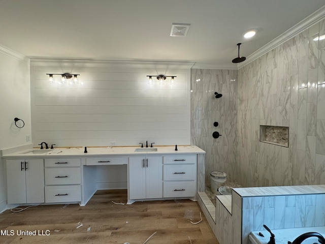 bathroom with hardwood / wood-style flooring, ornamental molding, vanity, and a tile shower