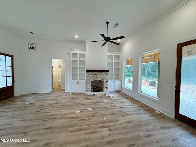 unfurnished living room featuring crown molding, a stone fireplace, built in features, and light hardwood / wood-style floors