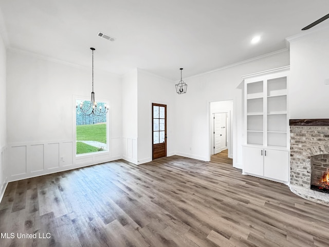 949 Mullican Rd, Florence, MS 39073 - unfurnished living room featuring a chandelier, wood finished floors, crown molding, a fireplace, and a wainscoted wall