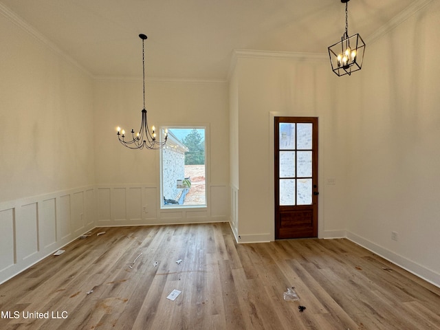 unfurnished dining area with ornamental molding, a chandelier, and light wood-type flooring