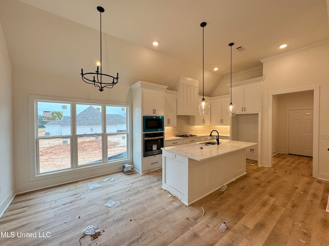 kitchen with built in microwave, white cabinetry, sink, and oven