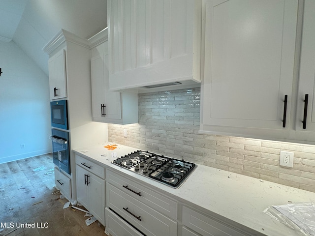 kitchen with white cabinetry, light stone countertops, decorative backsplash, oven, and stainless steel gas stovetop