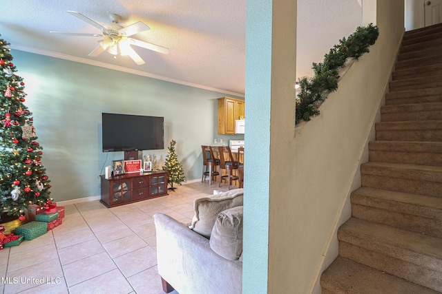 tiled living room with a textured ceiling, ceiling fan, and ornamental molding