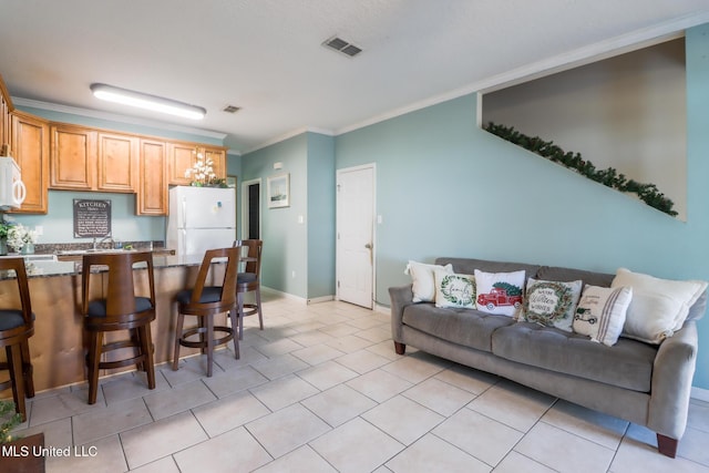 kitchen with a kitchen breakfast bar, white appliances, crown molding, sink, and light tile patterned floors