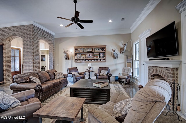 living area with a ceiling fan, crown molding, a fireplace, and brick wall