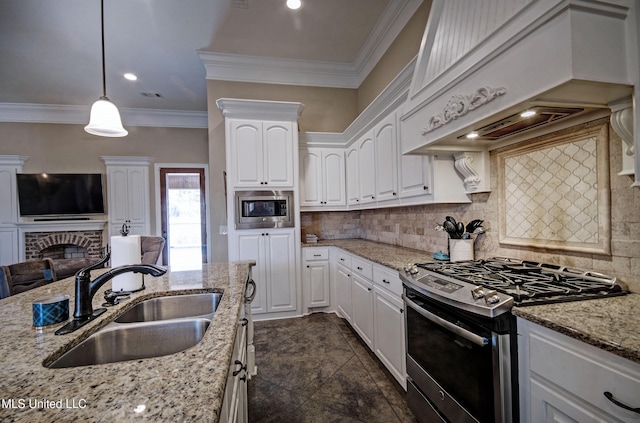 kitchen with premium range hood, a sink, stainless steel appliances, crown molding, and a brick fireplace