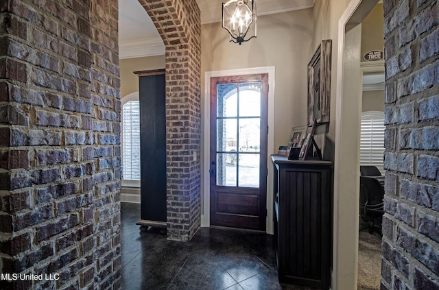 foyer featuring arched walkways, a notable chandelier, dark tile patterned floors, and crown molding