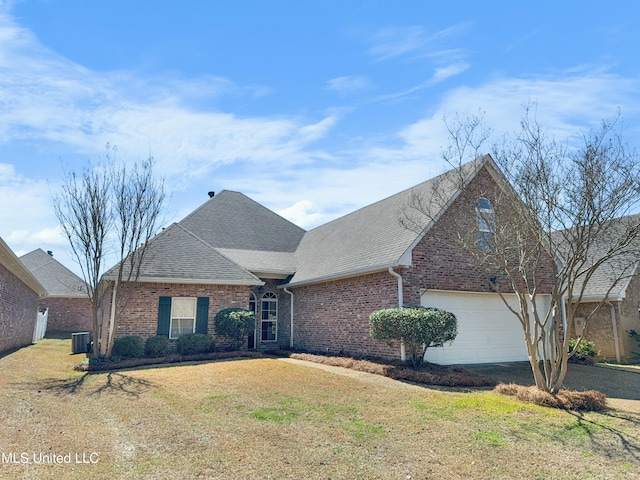 traditional-style home featuring driveway, a front yard, a shingled roof, a garage, and brick siding