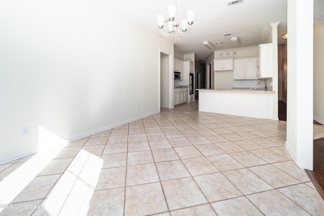 unfurnished living room featuring visible vents, a sink, light tile patterned flooring, baseboards, and a chandelier