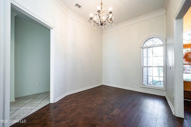 empty room with a wealth of natural light, visible vents, wood finished floors, and ornamental molding