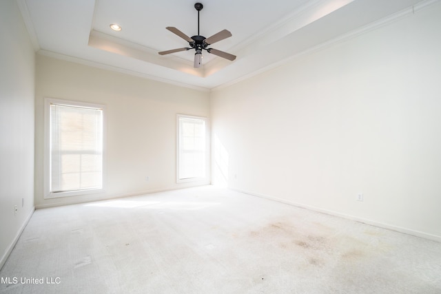 unfurnished room featuring a raised ceiling, plenty of natural light, crown molding, and carpet