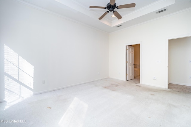 empty room featuring a tray ceiling, crown molding, visible vents, and light carpet