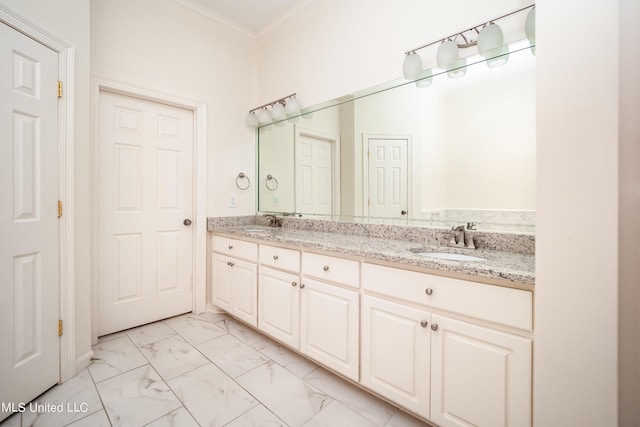 full bath featuring double vanity, marble finish floor, crown molding, and a sink