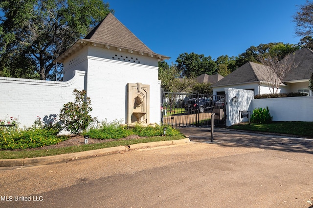 view of front of house with a gate, brick siding, roof with shingles, and fence