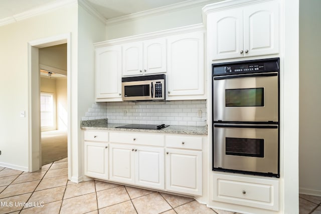 kitchen with light tile patterned flooring, appliances with stainless steel finishes, white cabinetry, crown molding, and backsplash