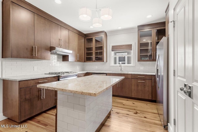 1309 Bowen Ave, Ocean Springs, MS 39564 - kitchen featuring under cabinet range hood, appliances with stainless steel finishes, backsplash, and light wood-style flooring