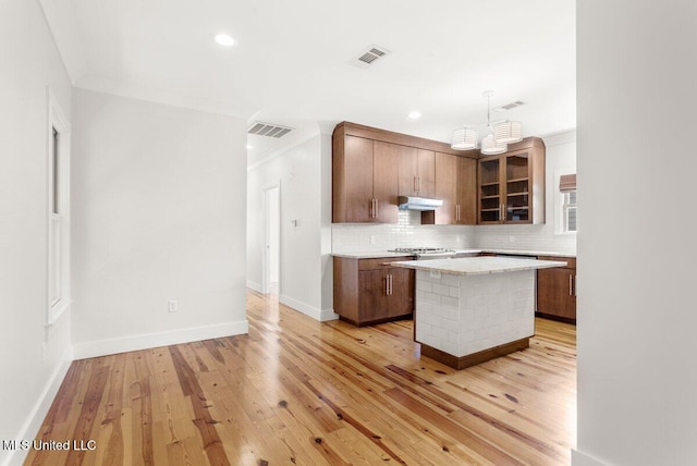 1309 Bowen Ave, Ocean Springs, MS 39564 - kitchen with under cabinet range hood, decorative backsplash, light wood-style floors, glass insert cabinets, and recessed lighting