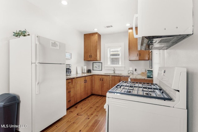 1309 Bowen Ave, Ocean Springs, MS 39564 - kitchen featuring white appliances, a sink, brown cabinetry, light wood-style flooring, and ventilation hood