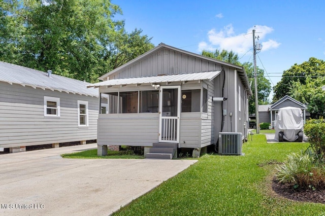 1309 Bowen Ave, Ocean Springs, MS 39564 - view of front facade with cooling unit, a front lawn, and a sunroom