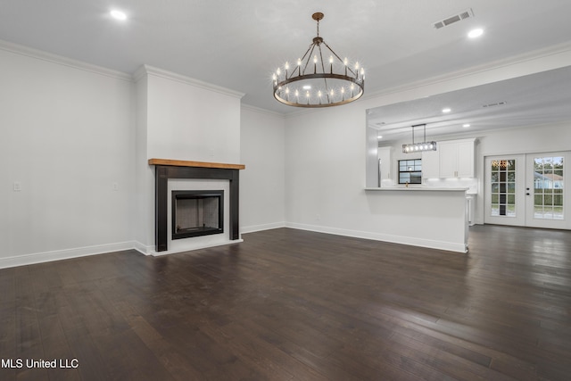 unfurnished living room featuring a chandelier, dark hardwood / wood-style flooring, ornamental molding, and french doors