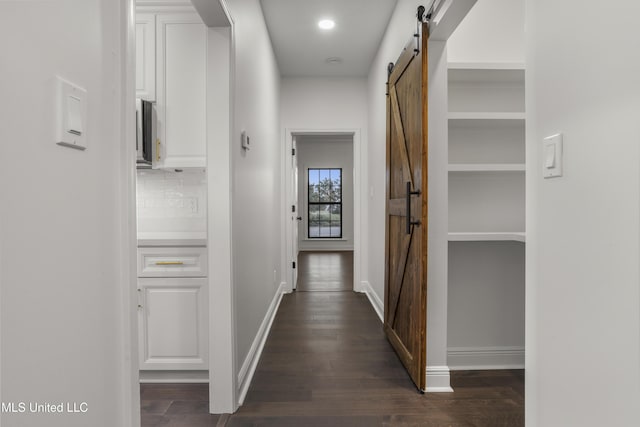 corridor with a barn door and dark hardwood / wood-style flooring