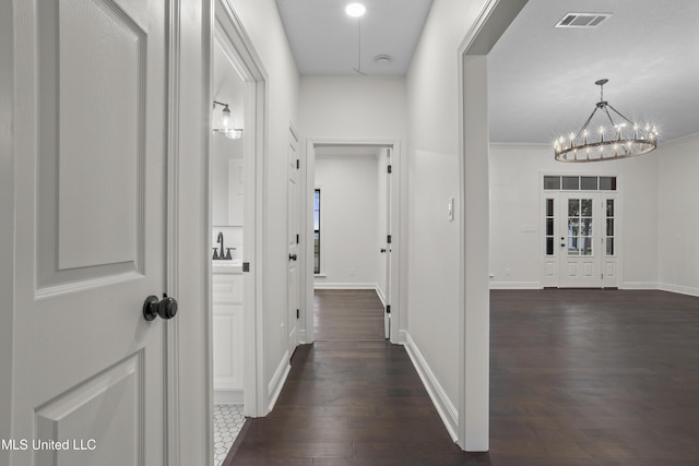 corridor with a chandelier, dark hardwood / wood-style flooring, and ornamental molding