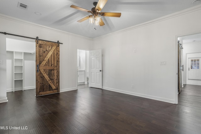 unfurnished room featuring a barn door, dark wood-type flooring, ceiling fan, and ornamental molding