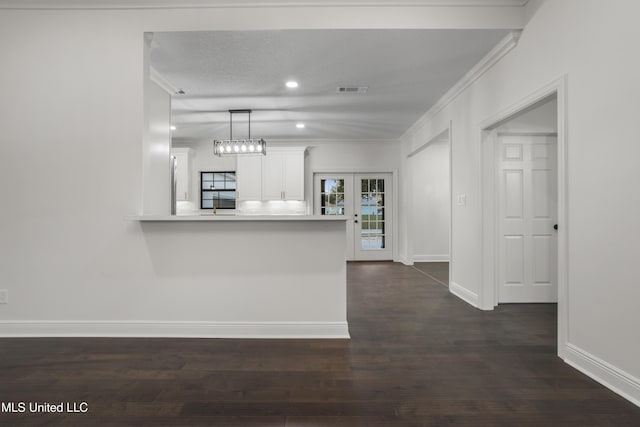 kitchen featuring kitchen peninsula, dark wood-type flooring, crown molding, decorative light fixtures, and white cabinets