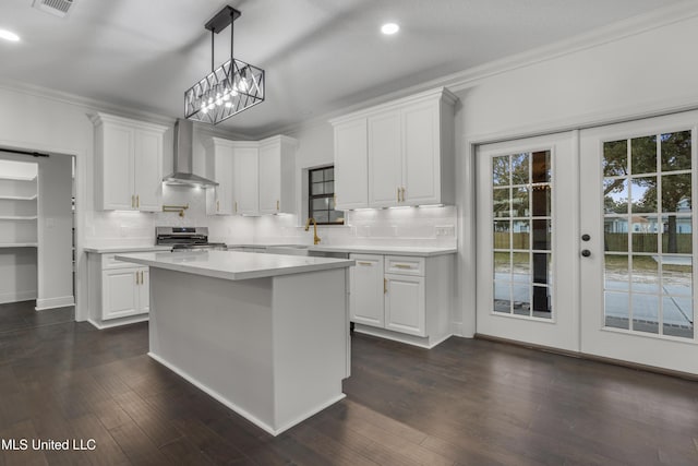 kitchen with gas stove, white cabinets, and wall chimney exhaust hood