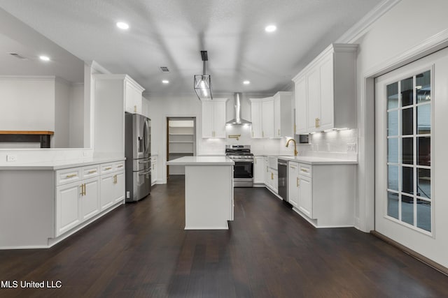 kitchen with white cabinets, wall chimney exhaust hood, a kitchen island, and stainless steel appliances