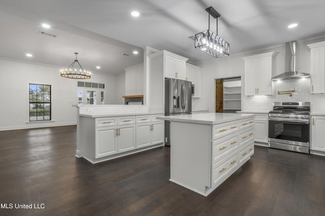 kitchen with white cabinets, decorative light fixtures, wall chimney range hood, and appliances with stainless steel finishes