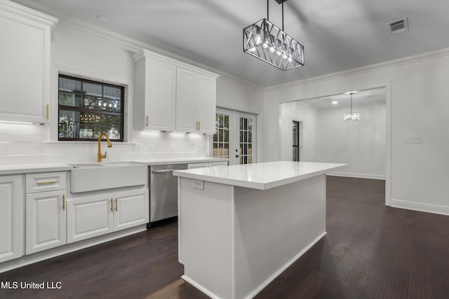 kitchen featuring backsplash, stainless steel dishwasher, sink, white cabinetry, and a kitchen island