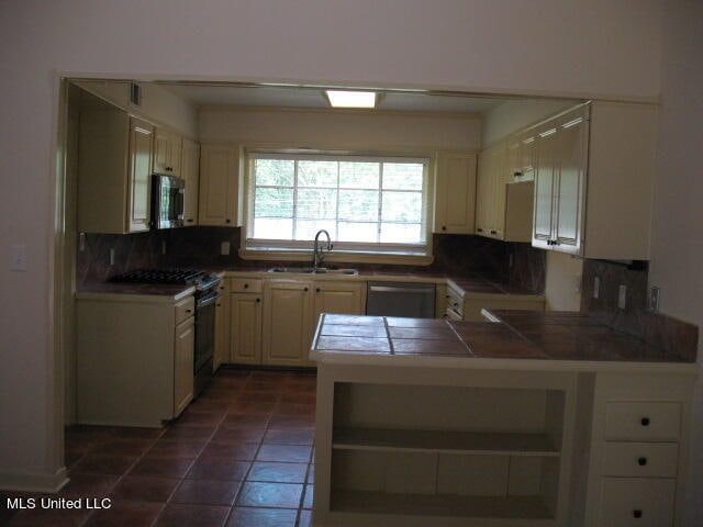 kitchen featuring tile counters, kitchen peninsula, stainless steel appliances, backsplash, and sink