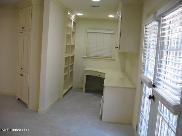 hall featuring light carpet, ornamental molding, and plenty of natural light