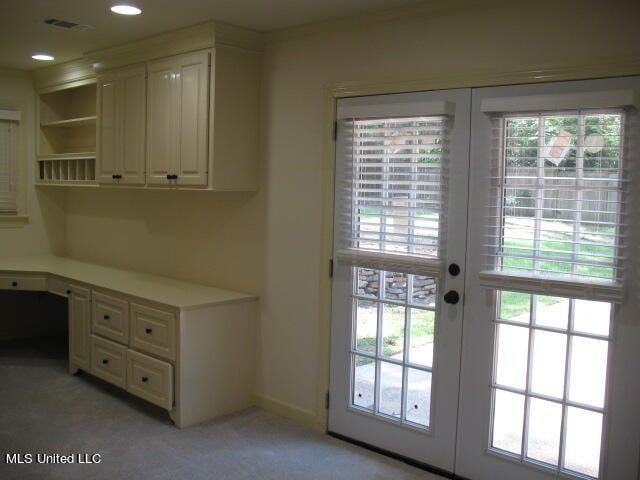 entryway with french doors, built in desk, and light colored carpet