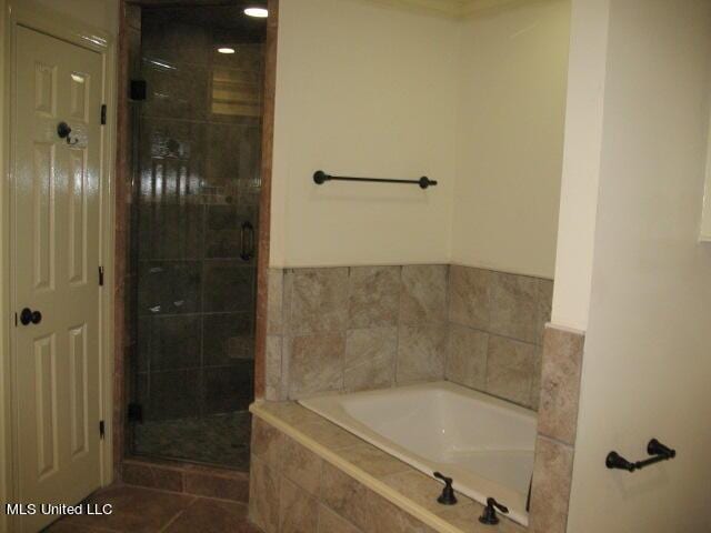 bathroom featuring a shower stall, tile patterned flooring, and a bath