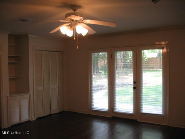 unfurnished room with ornamental molding, ceiling fan, built in features, and dark hardwood / wood-style flooring