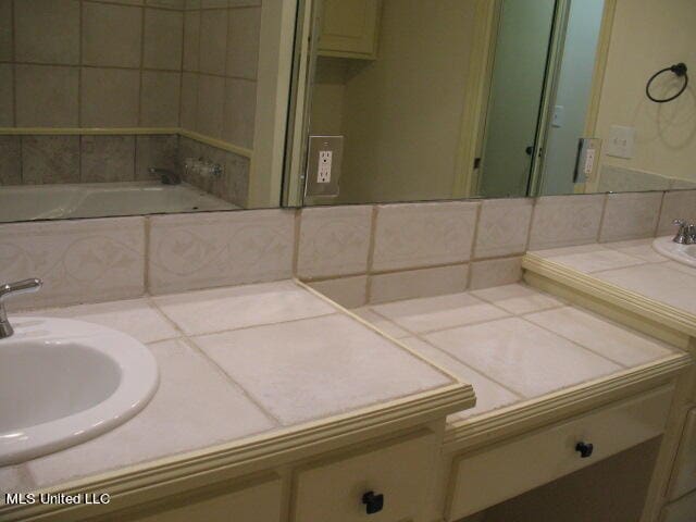 bathroom featuring vanity, decorative backsplash, and a tub to relax in