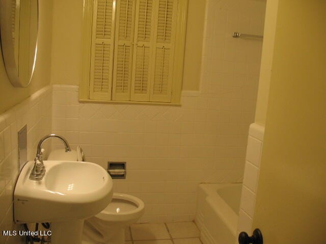 full bathroom featuring sink, toilet, tile walls, shower / tub combination, and tile patterned flooring