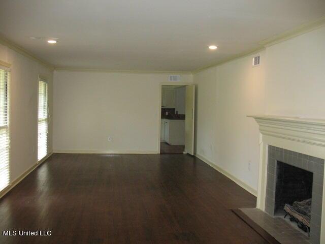 unfurnished living room featuring wood finished floors, recessed lighting, crown molding, baseboards, and a tiled fireplace