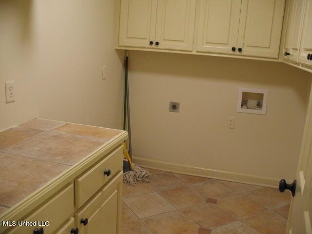 clothes washing area featuring cabinet space, light tile patterned flooring, electric dryer hookup, baseboards, and hookup for a washing machine