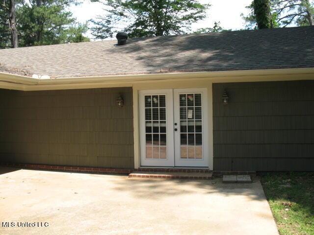 property entrance with a shingled roof, a patio, and french doors