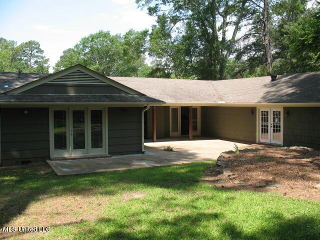 back of house featuring driveway, roof with shingles, a patio, and french doors
