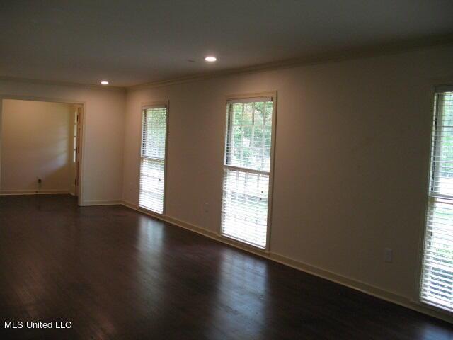 unfurnished room with baseboards, dark wood-style flooring, ornamental molding, and recessed lighting