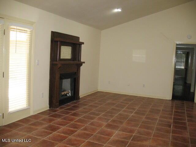 unfurnished living room featuring a fireplace, a healthy amount of sunlight, and tile patterned floors