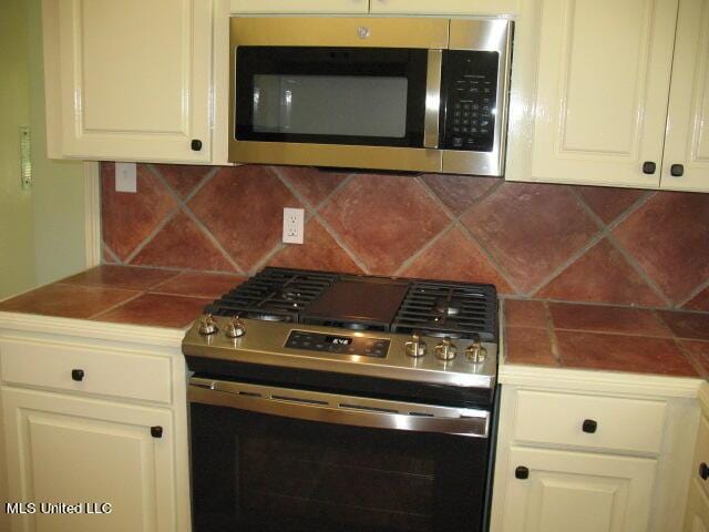 kitchen with white cabinets, decorative backsplash, stainless steel appliances, and tile counters