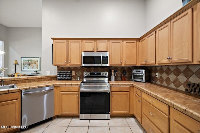 1510 Independence Blvd, Flowood, MS 39232 - kitchen featuring appliances with stainless steel finishes, light tile patterned floors, backsplash, and tile counters