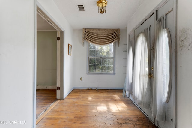 hallway with light hardwood / wood-style flooring and a textured ceiling