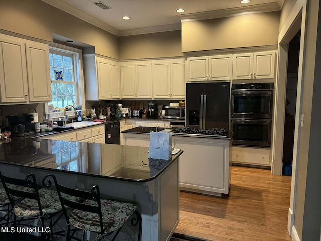 103 Park Ave, Indianola, MS 38751 - kitchen with dark stone counters, black appliances, sink, kitchen peninsula, and a breakfast bar area