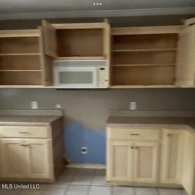 kitchen featuring cream cabinets, ornamental molding, and light tile patterned flooring